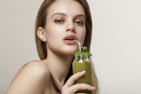 La ragazza beve un cocktail verde